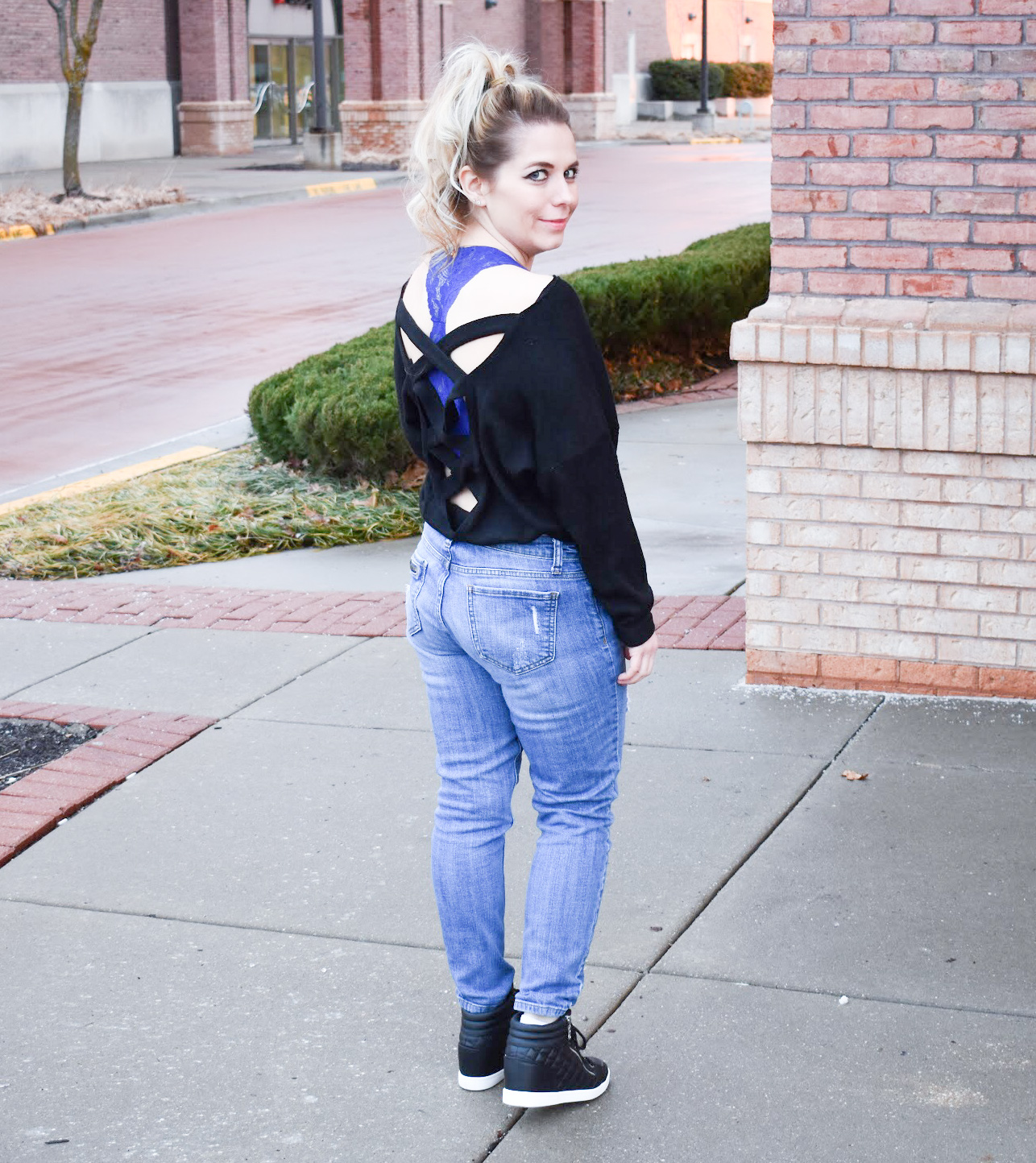 Black Criss-Cross Sweater + Bralette for Large Bust: This black criss-cross sweater styled with ripped jeans and black wedge sneakers is the perfect mix of sporty and sexy for your next date night! Plus, the perfect affordable bralette for large bust ladies. Fashion blogger COVET by tricia shows how to style a perfect date night look mixing black and denim.