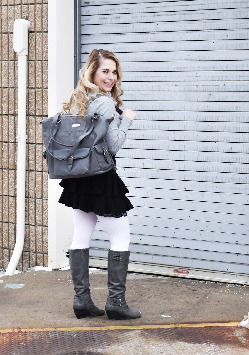 Fashion blogger COVET by tricia styles a ruffled black mini skirt with white tights, a grey bodysuit, grey wedge boots ,and a gorgeous Lily Jade diaper bag. This black mini skirt with ruffles is an affordable statement piece for your wardrobe. Check out this cute winter date night look from Kansas City fashion blogger COVET by tricia.