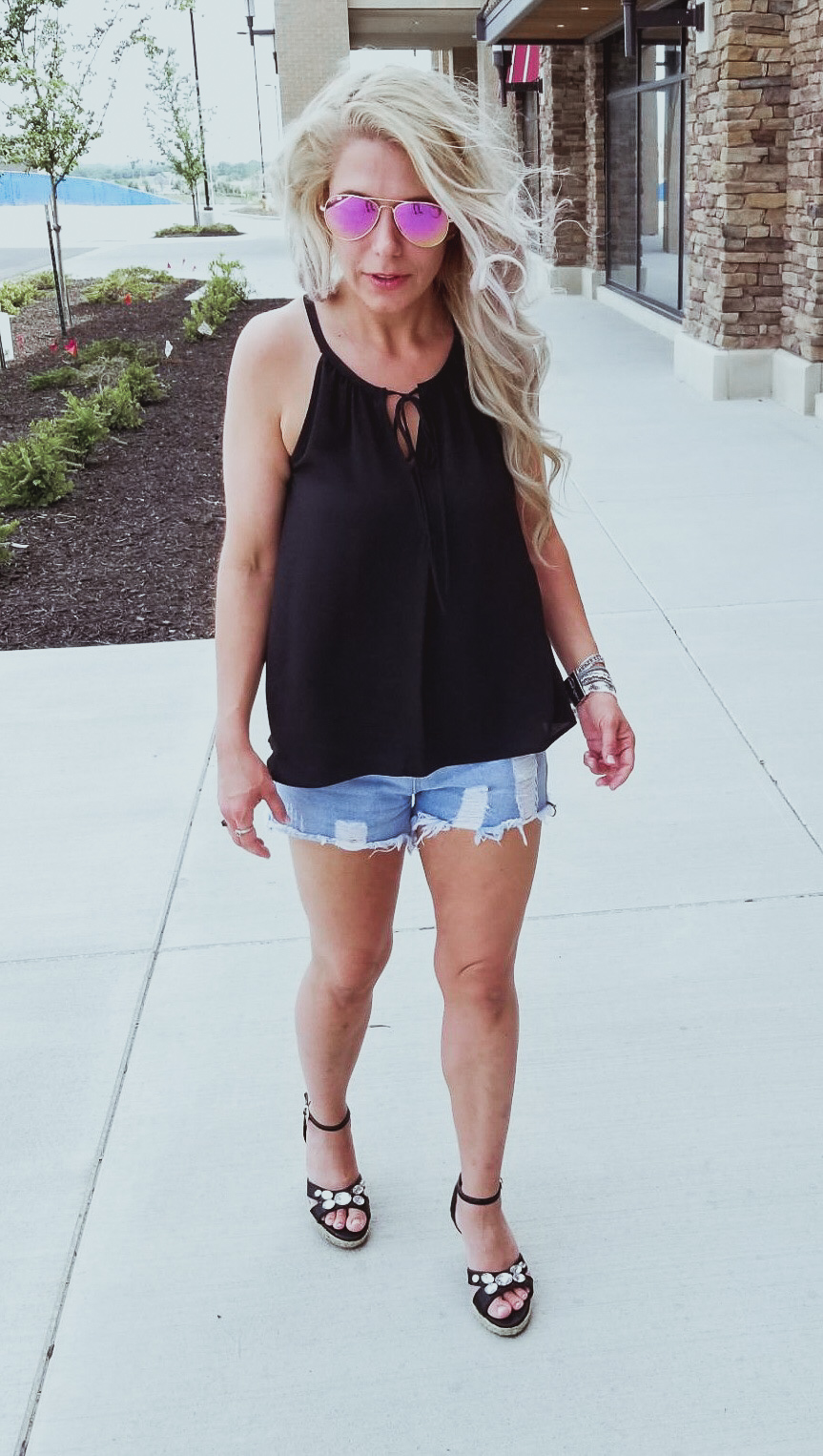 Casual Summer Outfit - Black Halter, Ripped Denim Shorts, and Black Wedges. Summer 2018 is in full swing and here's one of the hottest looks we've seen yet. Pair your ripped jean shorts with a black tank top for a casual summer outfit that's sure to impress. Don't forget the accessories, like the stylish Victoria Emerson bracelet featured here. Click for an exclusive Victoria Emerson coupon code!