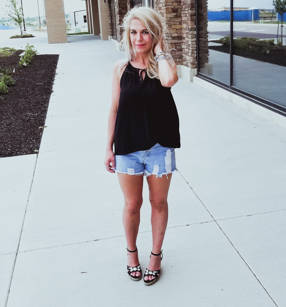 Casual Summer Outfit - Black Halter, Ripped Denim Shorts, and Black Wedges. Summer 2018 is in full swing and here's one of the hottest looks we've seen yet. Pair your ripped jean shorts with a black tank top for a casual summer outfit that's sure to impress. Don't forget the accessories, like the stylish Victoria Emerson bracelet featured here. Click for an exclusive Victoria Emerson coupon code!