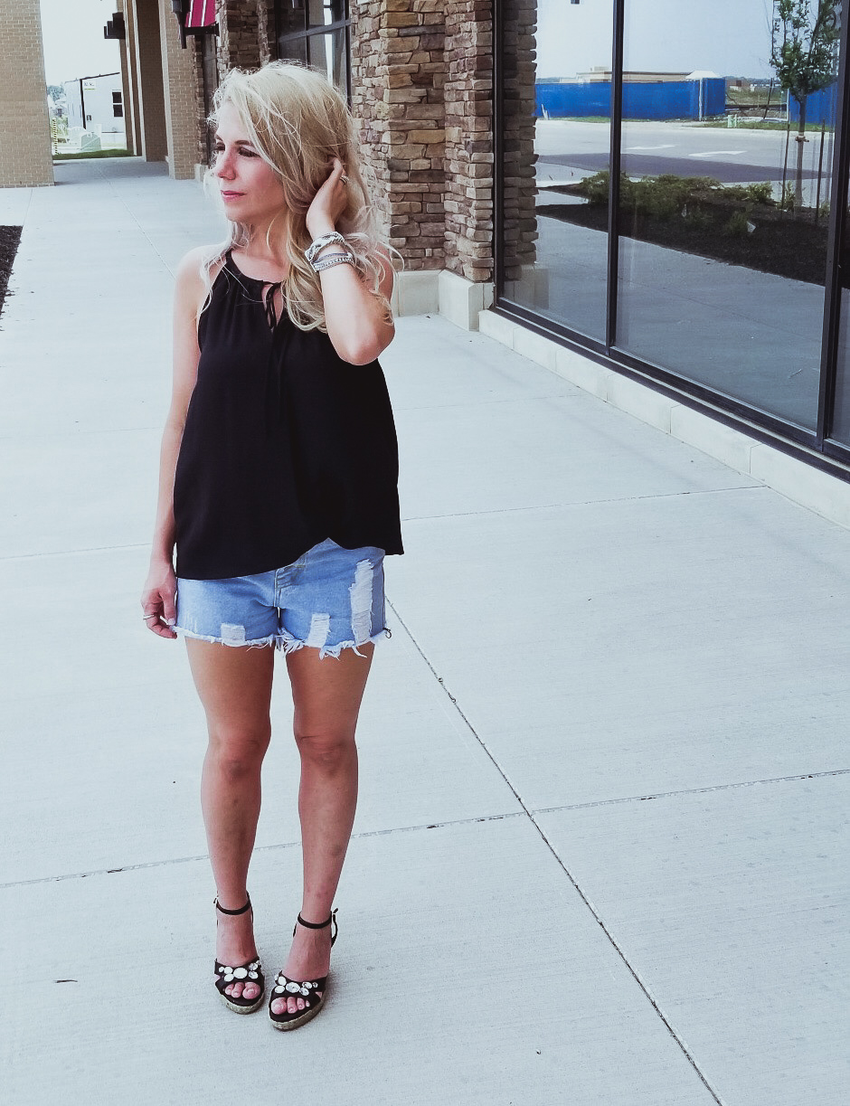 Casual Summer Outfit - Black Halter, Ripped Denim Shorts, and Black Wedges. Summer 2018 is in full swing and here's one of the hottest looks we've seen yet. Pair your ripped jean shorts with a black tank top for a casual summer outfit that's sure to impress. Don't forget the accessories, like the stylish Victoria Emerson bracelet featured here. Click for an exclusive Victoria Emerson coupon code!