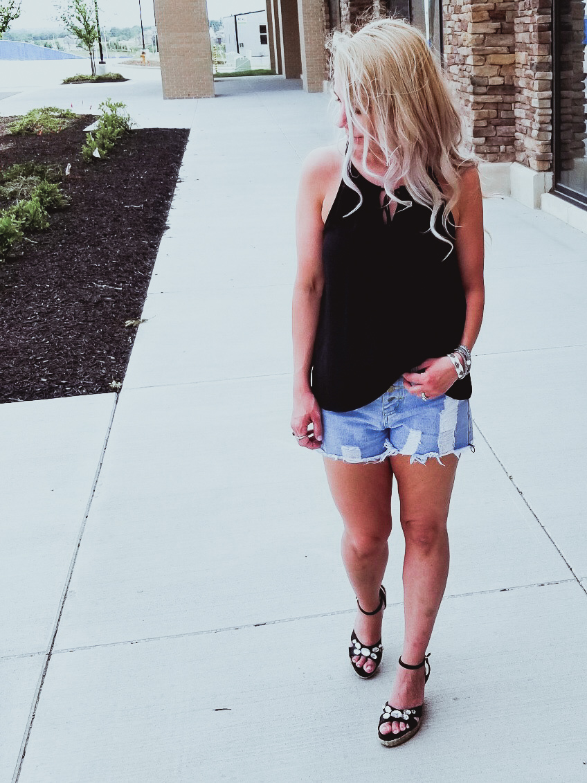 Casual Summer Outfit - Black Halter, Ripped Denim Shorts, and Black Wedges. Summer 2018 is in full swing and here's one of the hottest looks we've seen yet. Pair your ripped jean shorts with a black tank top for a casual summer outfit that's sure to impress. Don't forget the accessories, like the stylish Victoria Emerson bracelet featured here. Click for an exclusive Victoria Emerson coupon code!