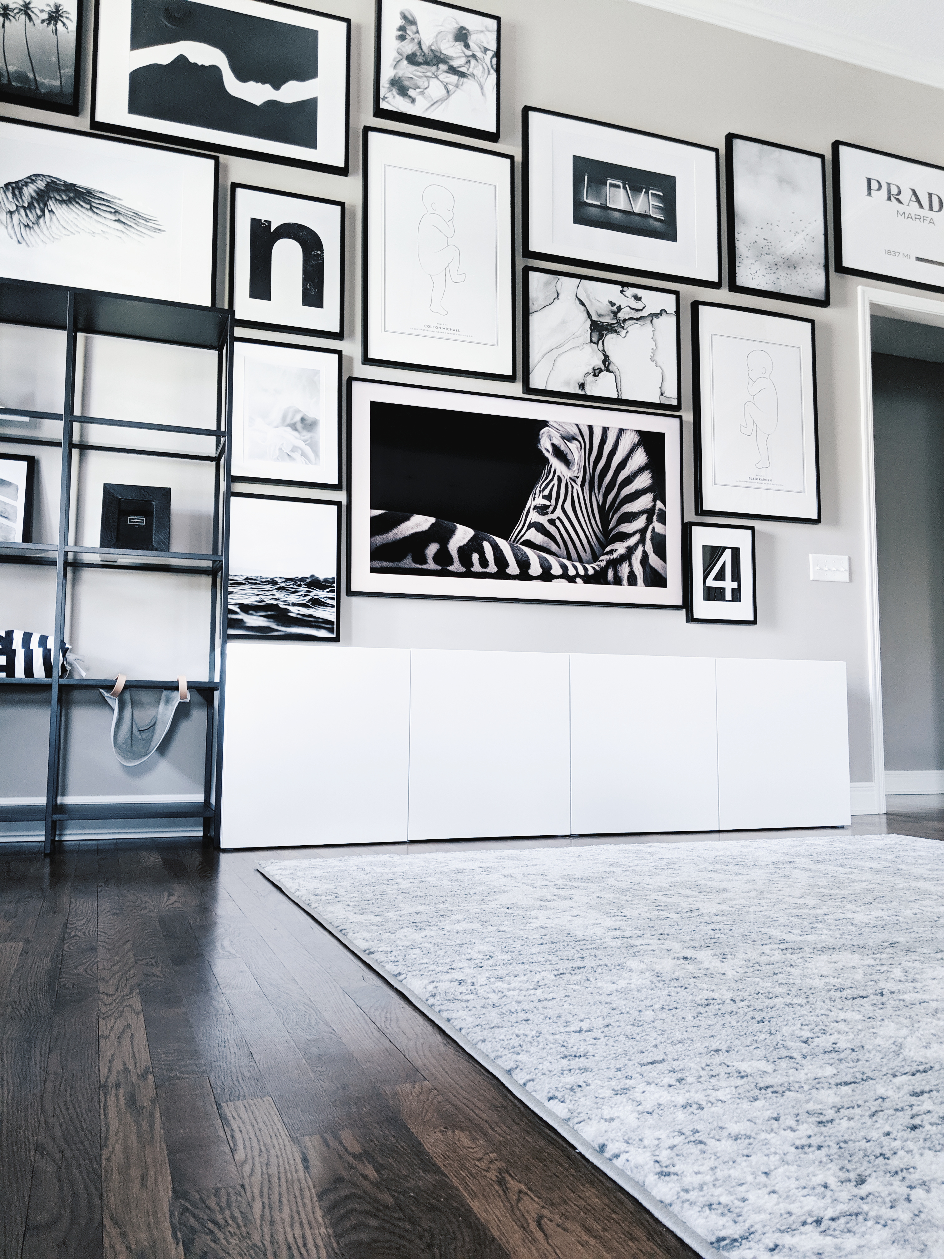 Living Room Gallery Wall Ideas: Looking for gallery wall ideas? This black and white gallery wall is a total showstopper. This is one of the best gallery walls I've ever seen! Includes Desenio posters, Samsung The Frame TV, Ikea Besta as a TV stand, Ikea Ribba frame gallery wall, Ikea Vittsjo shelves. #gallerywall #blackandwhite #monochrome